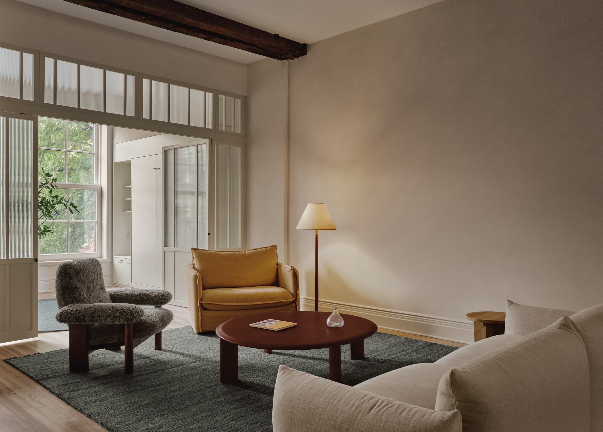 LOOKING TOWARD LIVING ROOM WITH YELLOW CHAIR AND GLASS DIVIDING WALL